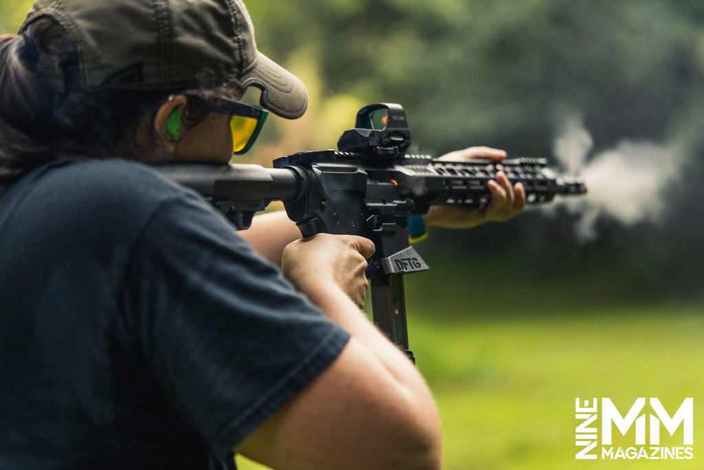 a photo of a woman shooting a pcc rifle at a gun range