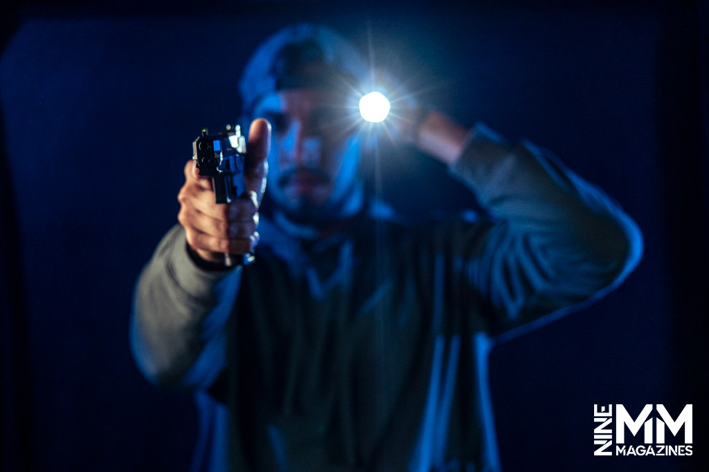 a photo of a man with a handgun and flashlight