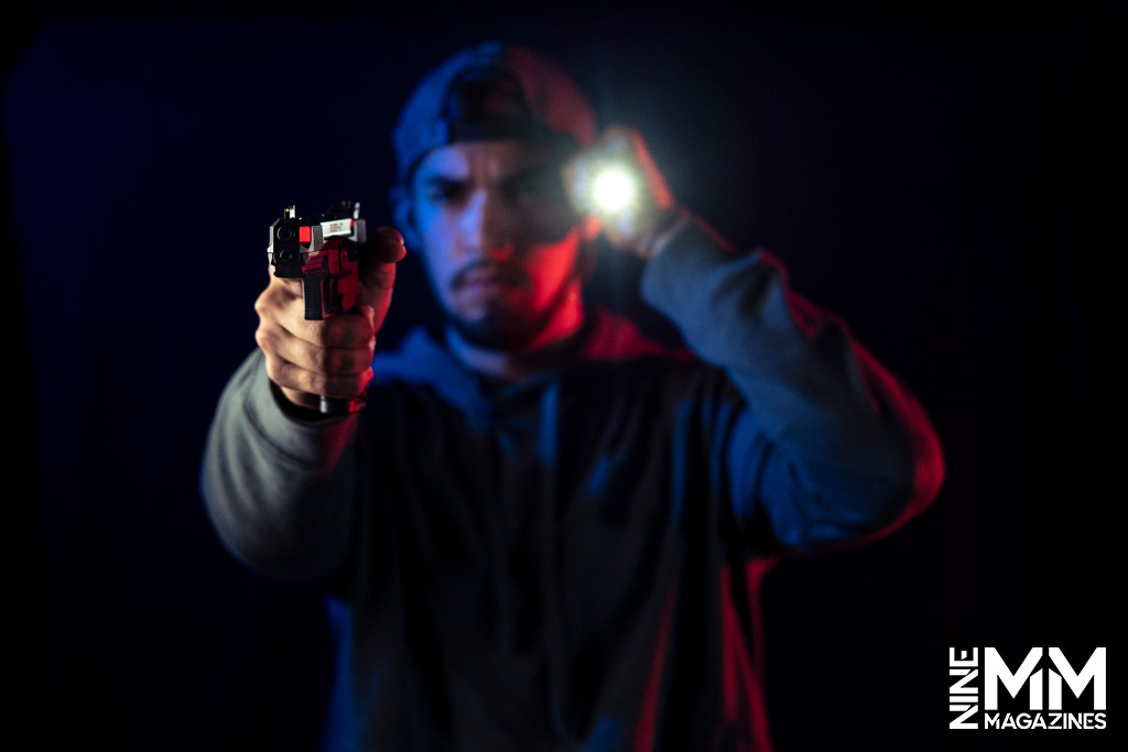 a photo of a man holding a handgun and a flashlight