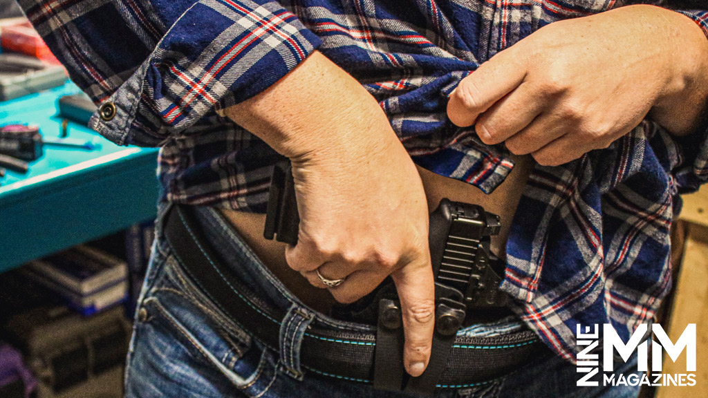 a photo of a woman drawing a handgun from the appendix position