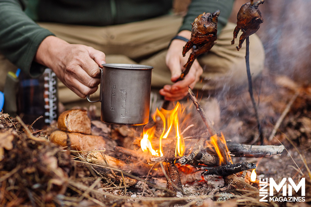 a photo of a man cooking food in the woods