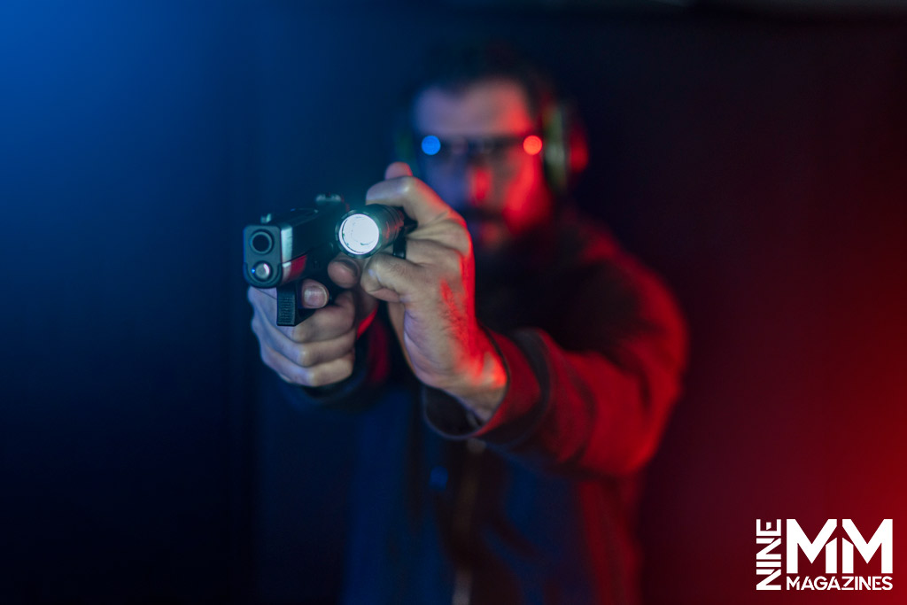 a photo of a man using a surefire flashlight with a handgun