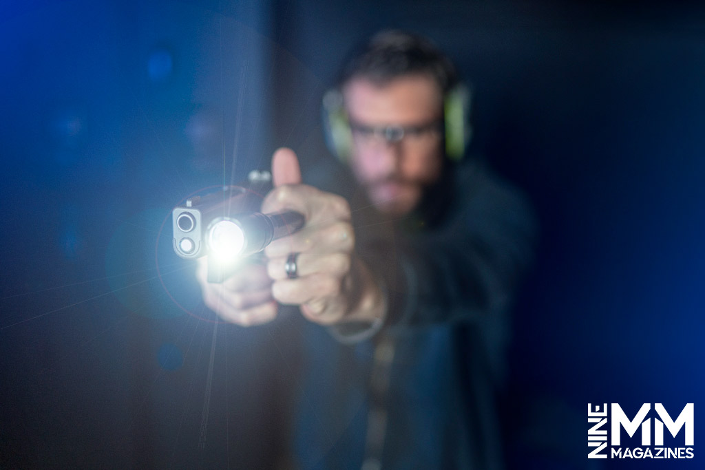 a photo of a man using a flashlight with a handgun