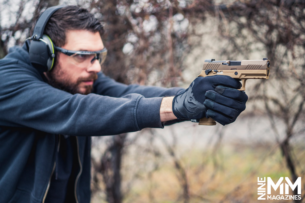 a photo of a man shooting a sig sauer pistol outdoors