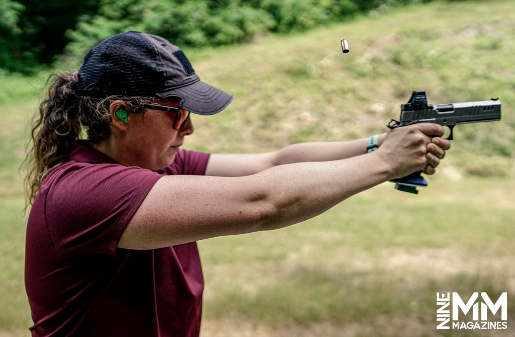 a photo of a woman shooting a handgun outdoors