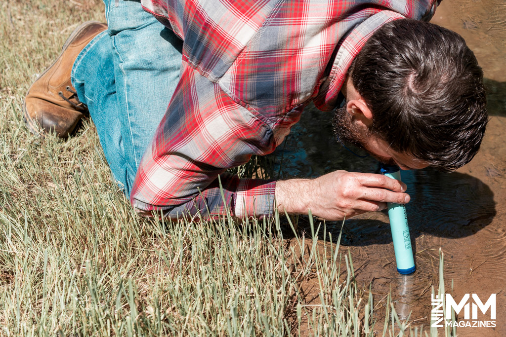 a photo of a man drinking out of a lifestraw