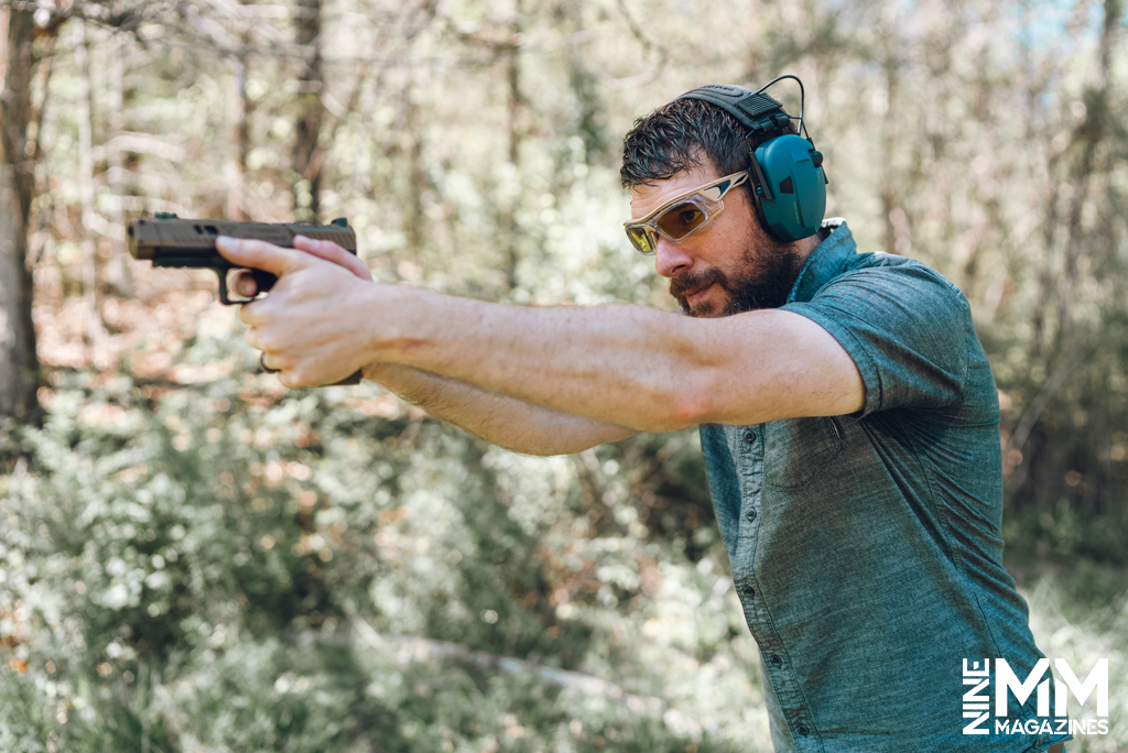 a photo of a man shooting a handgun with ear and eye protection