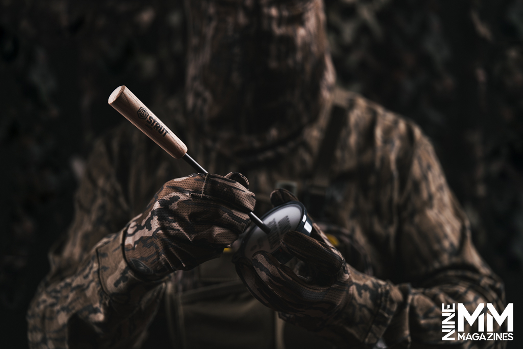 a photo of a hunter using a turkey call in the woods